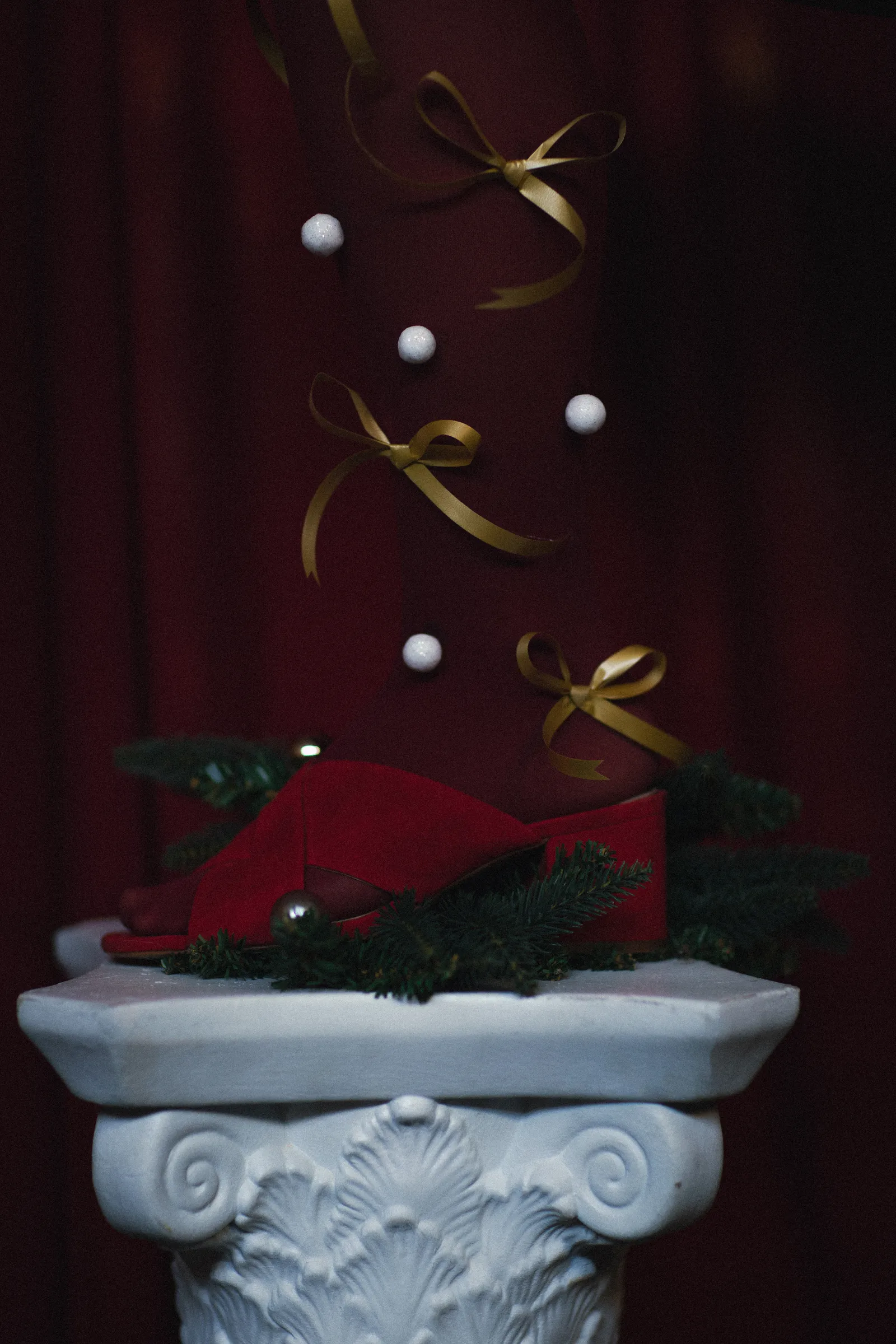 Kerstdecoratie met gouden linten en een rode strik op een witte zuil
